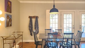 Un comedor con una mesa, sillas, una lámpara colgante y obras de arte en las paredes.