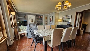 Un coin repas comprenant une table, des chaises, un lustre et une bibliothèque.