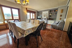 A dining area with a table, chairs, and a chandelier. There is a bookshelf with books and decorative items. - 15A04 Duplex and Garage in Downtown by R2R Consulting (Llanes)