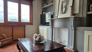 Une pièce avec une table en bois, une cheminée, un téléviseur et une fenêtre donnant sur un beau paysage.