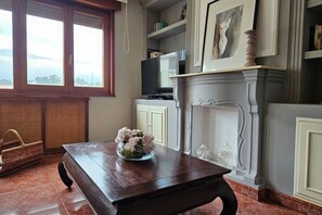 A room with a wooden table, a fireplace, a television, and a window with a view. - 15A04 Duplex and Garage in Downtown by R2R Consulting (Llanes)