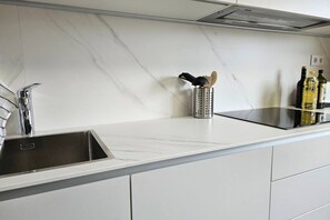 A kitchen with a stainless steel sink, a marble countertop, and a range hood. - 15A04 Duplex and Garage in Downtown by R2R Consulting (Llanes)
