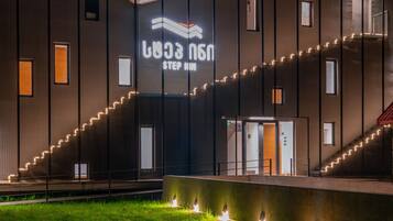 Un edificio moderno con un gran letrero iluminado que dice "STEP MIM" y una escalera bien iluminada que conduce a la entrada.