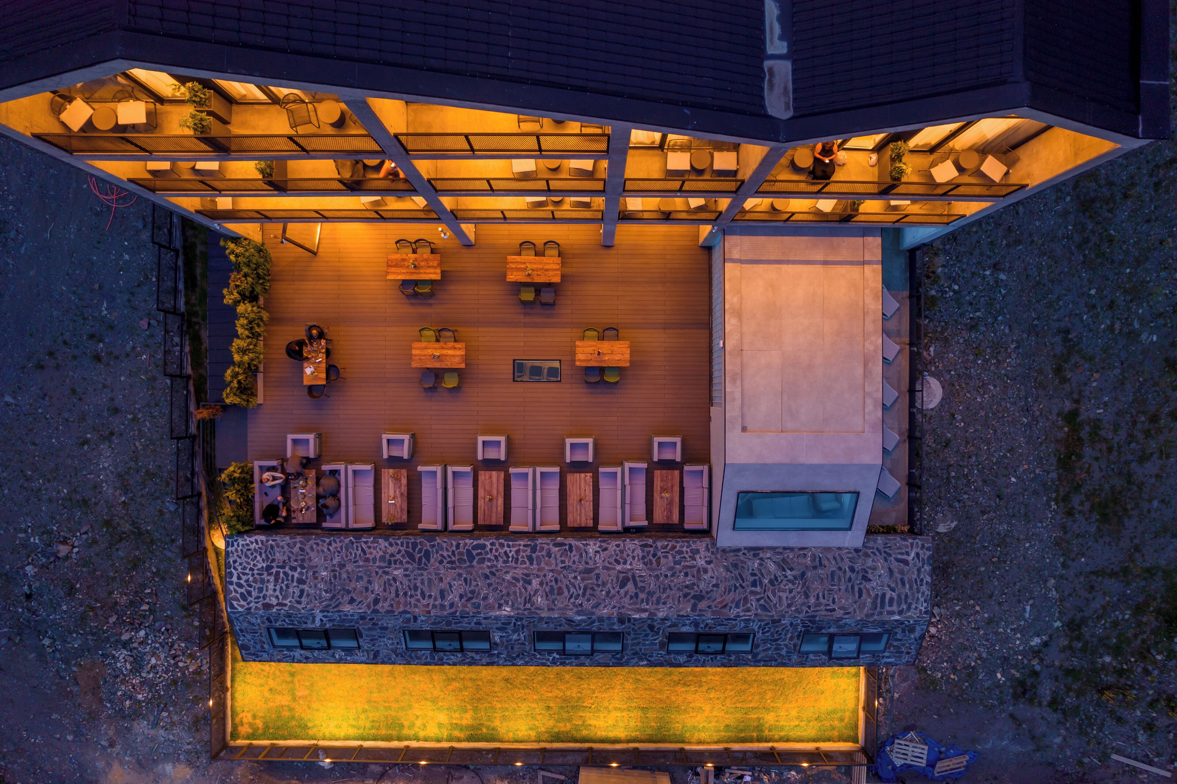 An aerial view of a restaurant with outdoor seating, a stone facade, and a modern design.