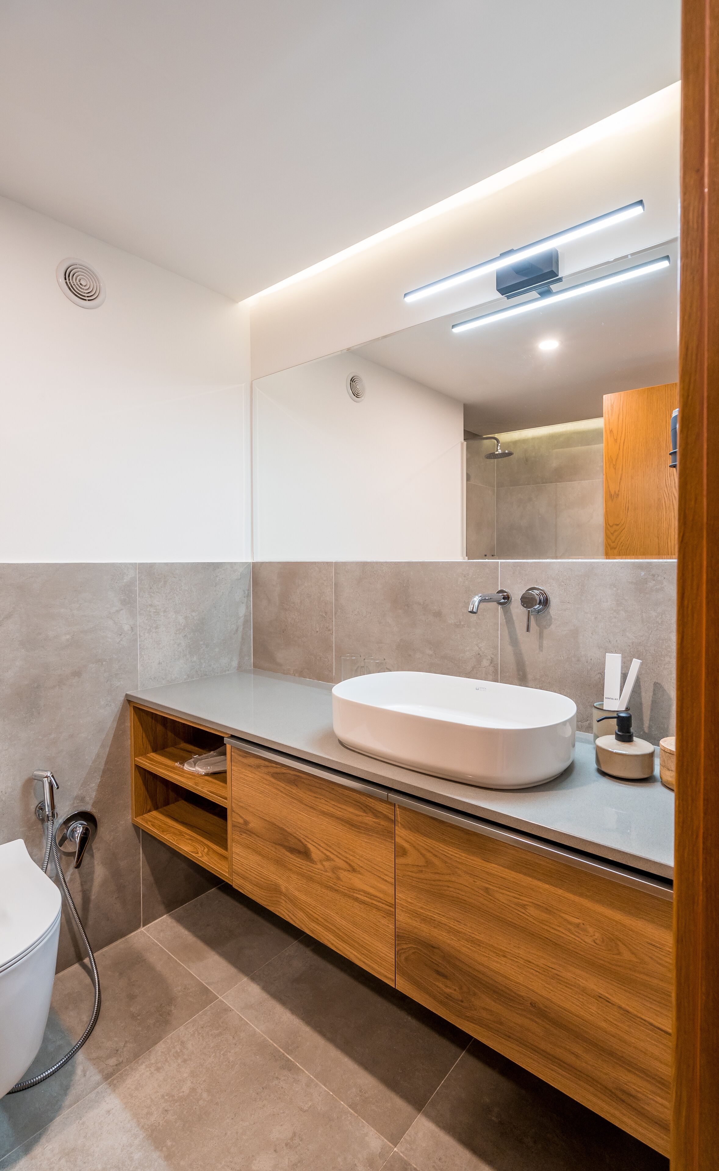 Un baño moderno con una bañera independiente, un tocador de madera y un espejo grande.
