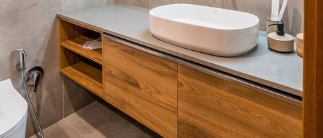 Un baño moderno con una bañera independiente, un tocador de madera y un espejo grande.