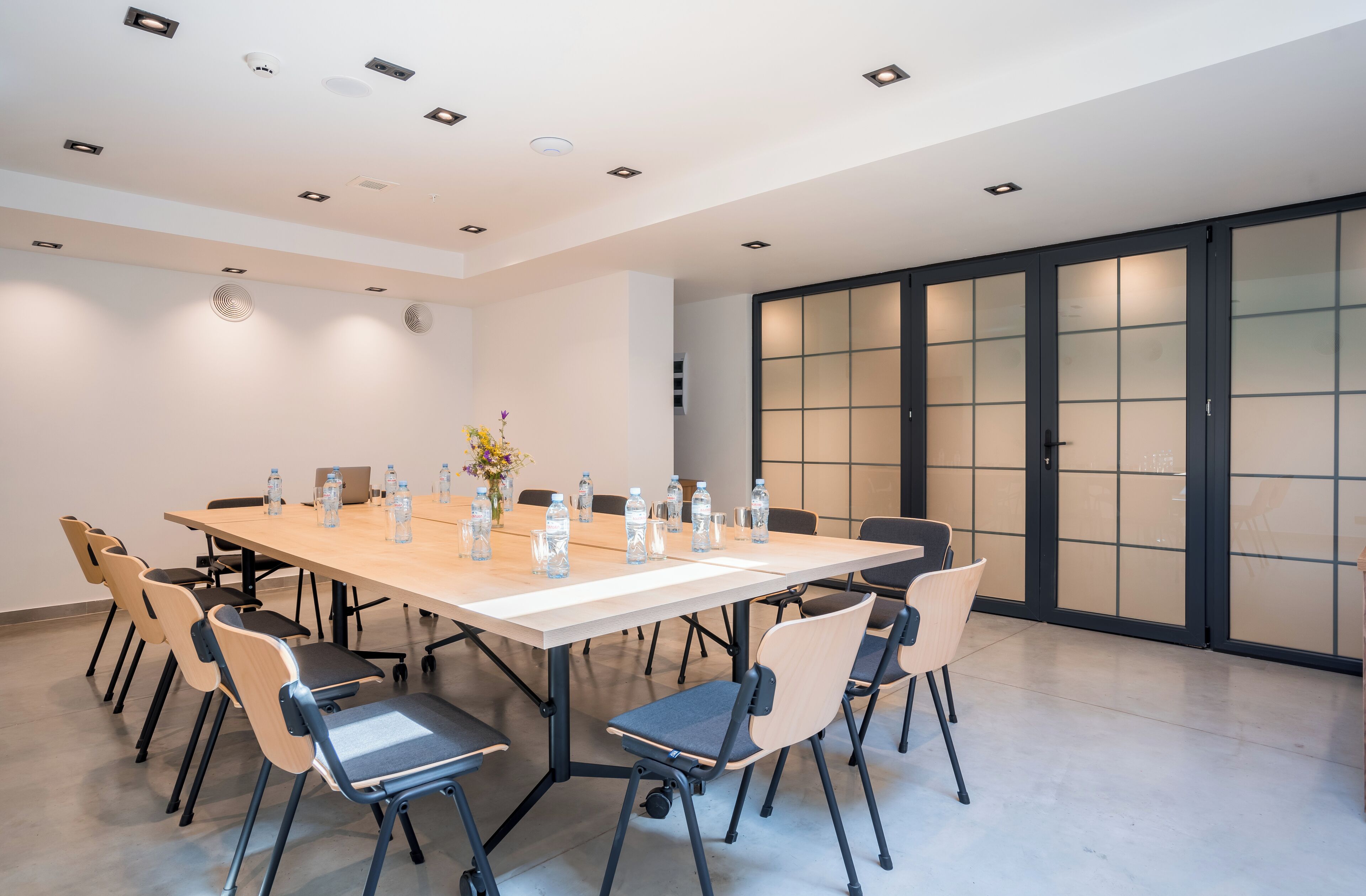 A conference room with a long table, chairs, and water bottles.