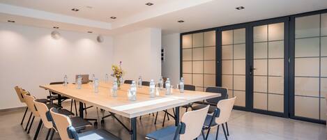 A conference room with a long table, chairs, and water bottles.