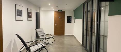A hallway with two rocking chairs, a wooden door, and a sign indicating a toilet.