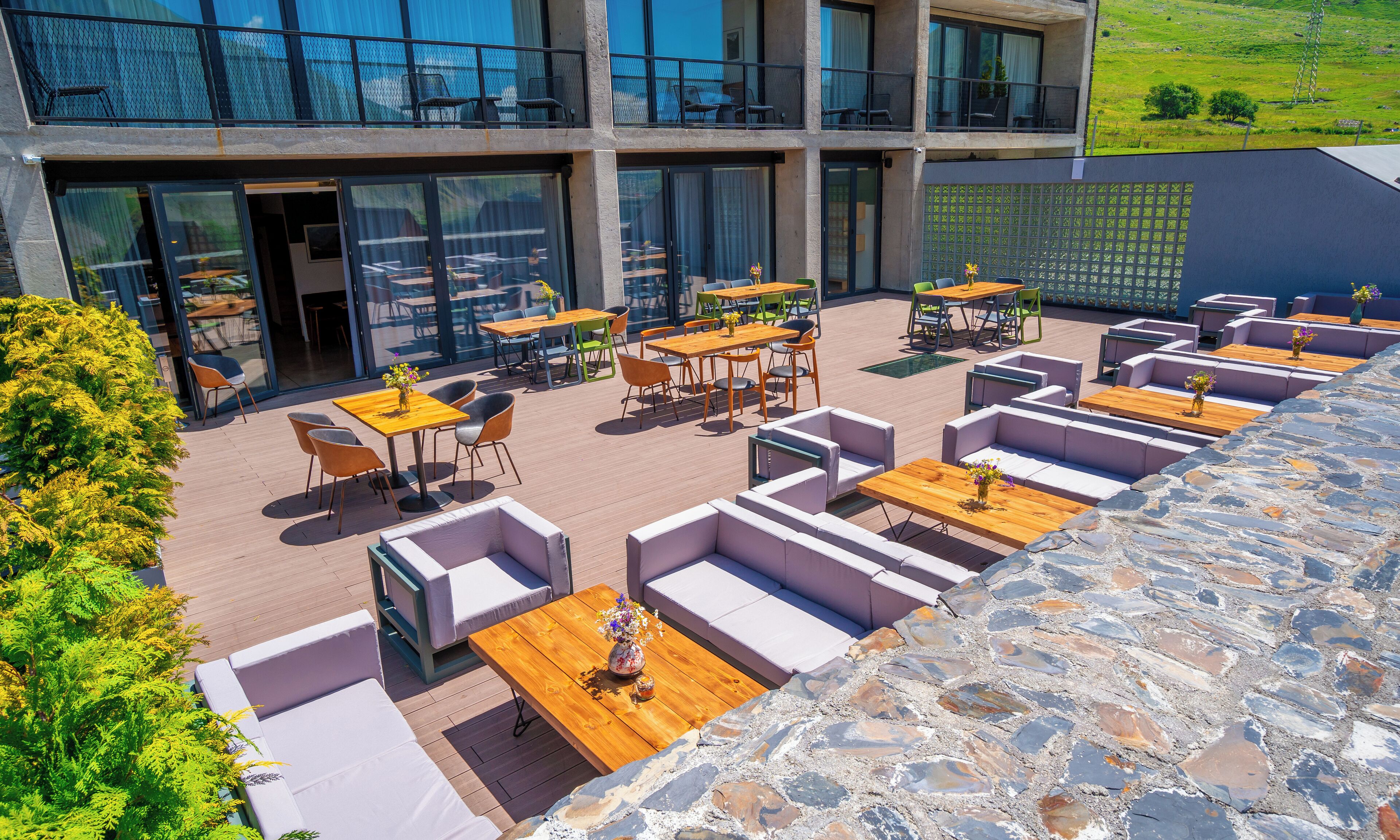 Una terrazza sul tetto con posti a sedere all'aperto, un muro in pietra e vista su un paesaggio verdeggiante.