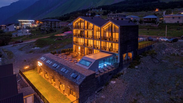 Un edificio moderno de varios pisos con amplios ventanales, techo plano y zona de piscina.