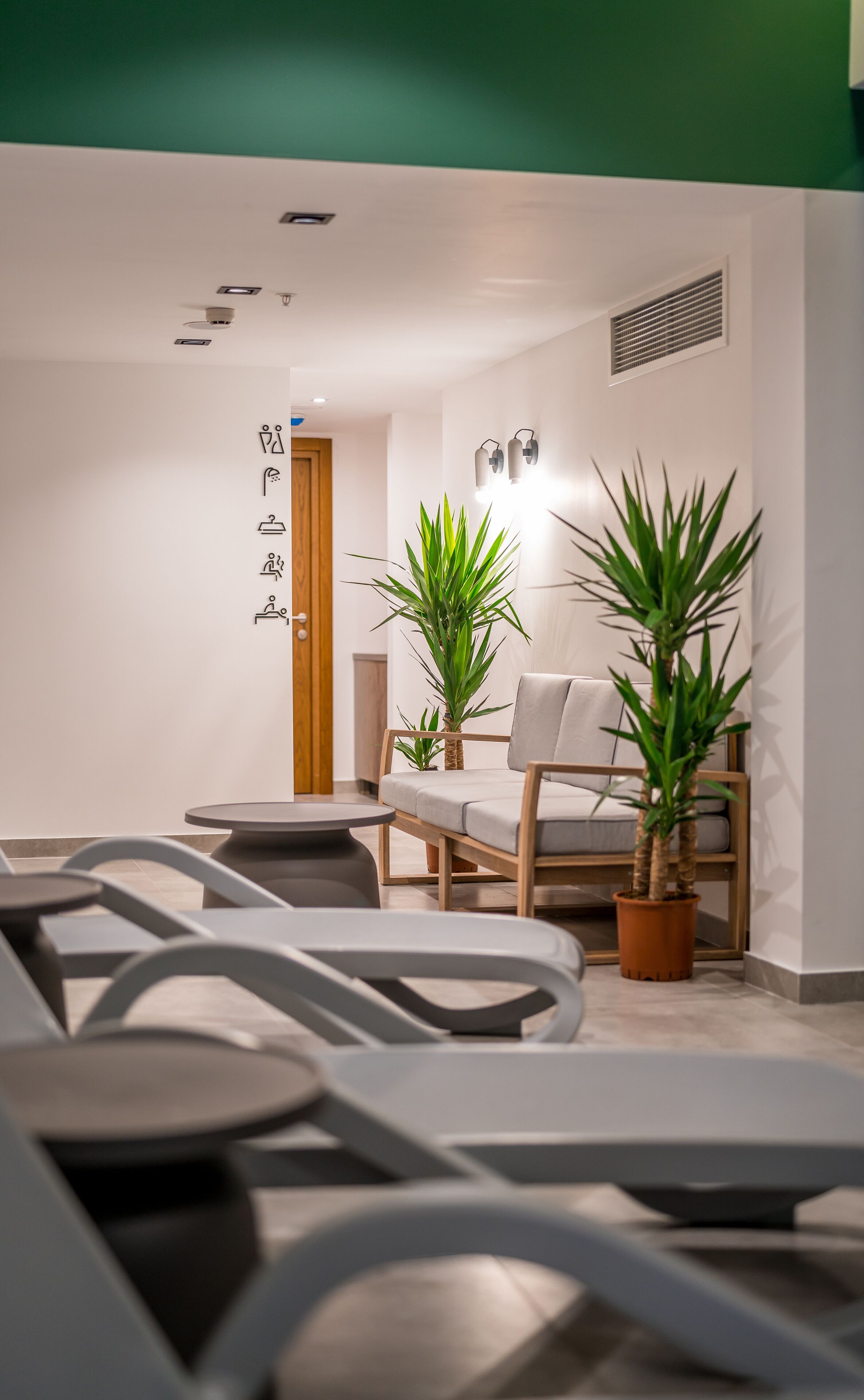 Un espace d’attente moderne, aménagé avec un canapé, des fauteuils et des plantes en pot.
