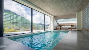 Una piscina interior con amplias ventanas y vistas a un paisaje montañoso.
