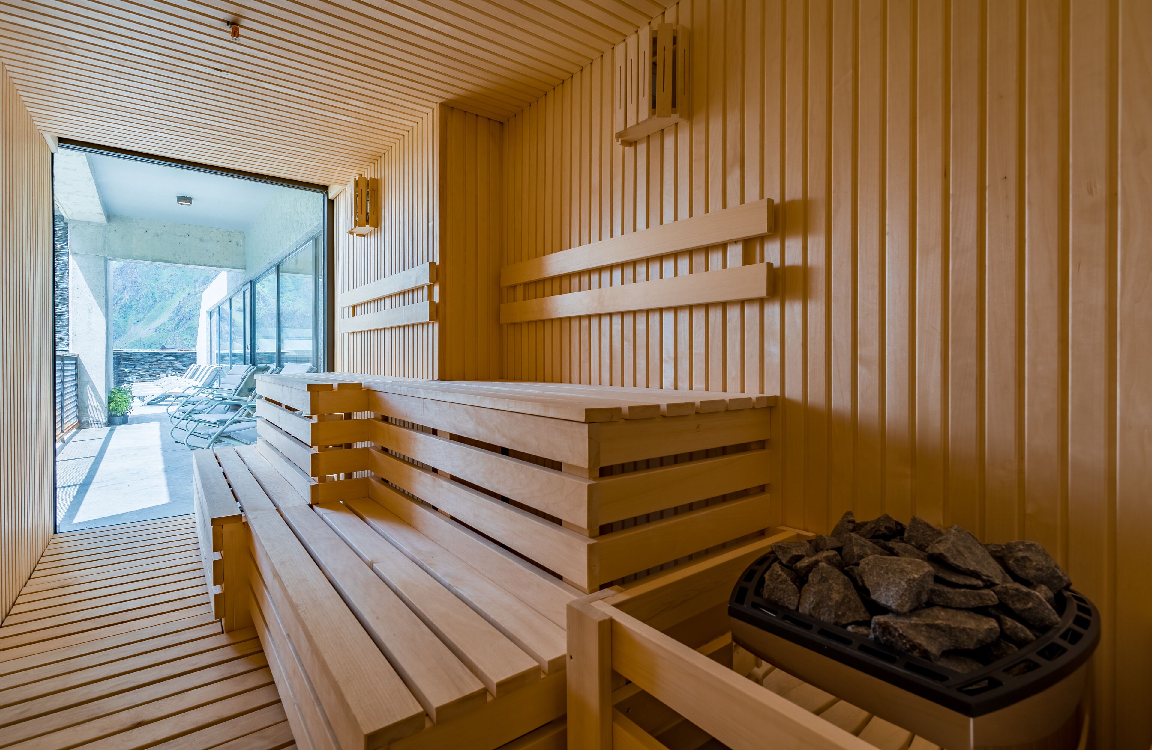 Un sauna avec des bancs en bois et un bassin en pierre.