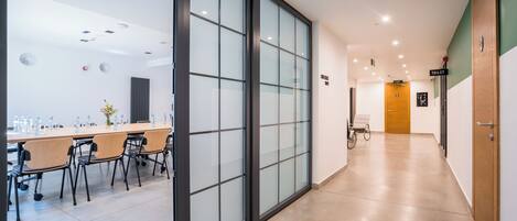 Un moderno vestíbulo de hotel con un largo pasillo, una recepción y una puerta de salida visible.