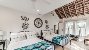 Camera da letto con due letti, una ventola a soffitto, decorazioni murali e soffitto in legno.