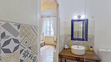 Un bagno con un lavandino bianco, uno specchio con cornice blu e piastrelle decorate.