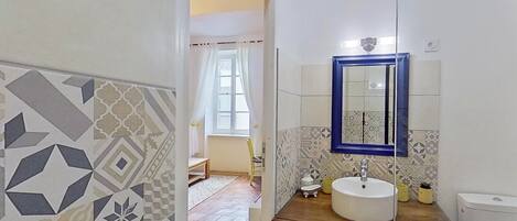 Un baño con un lavabo blanco, un espejo de marco azul y baldosas con diseño.