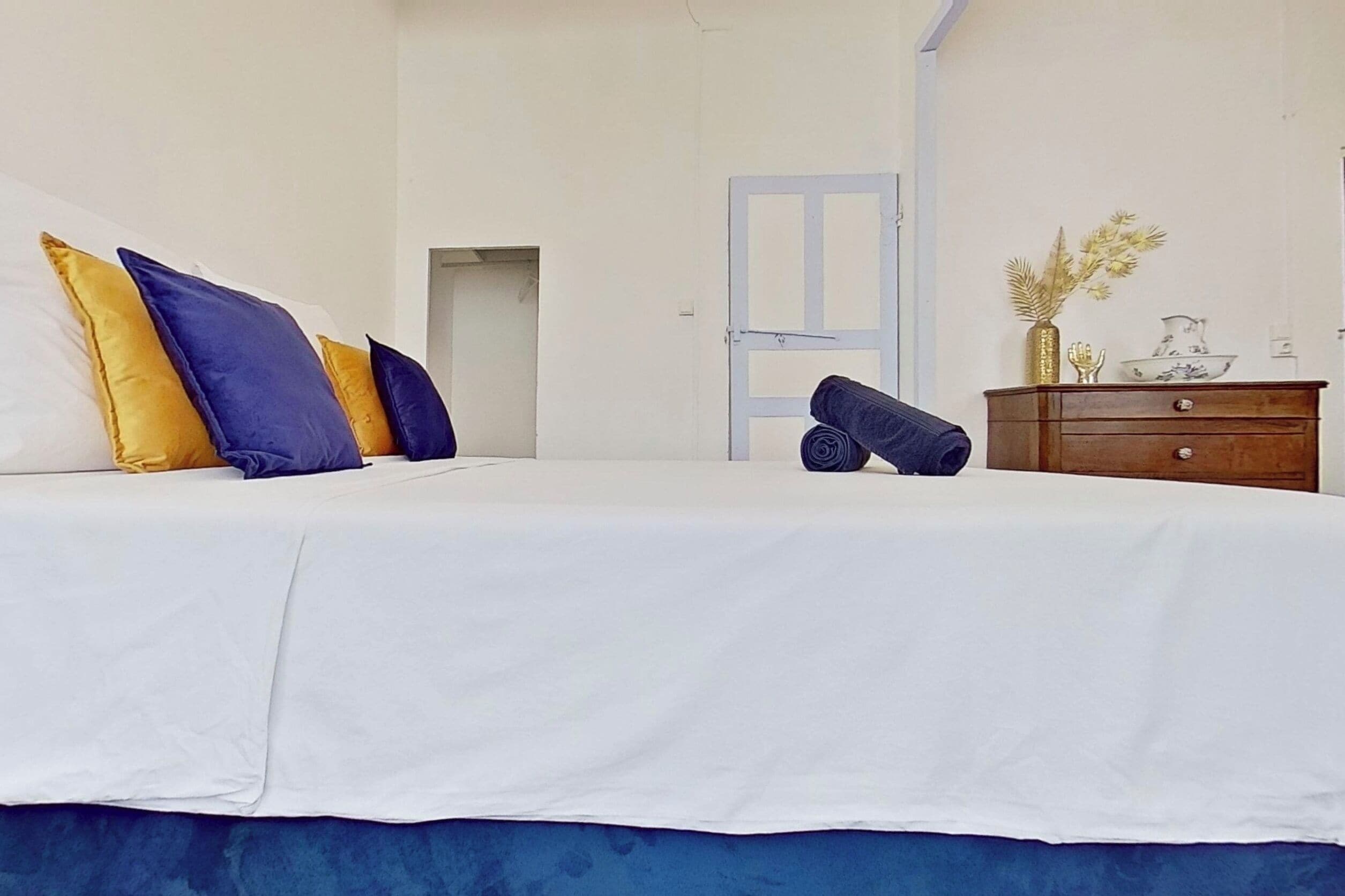 Un dormitorio con cama, almohadas, cómoda y puerta.