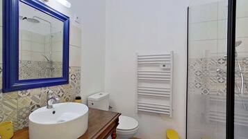 A bathroom with a white sink, a mirror with a blue frame, a toilet, and a shower enclosure.