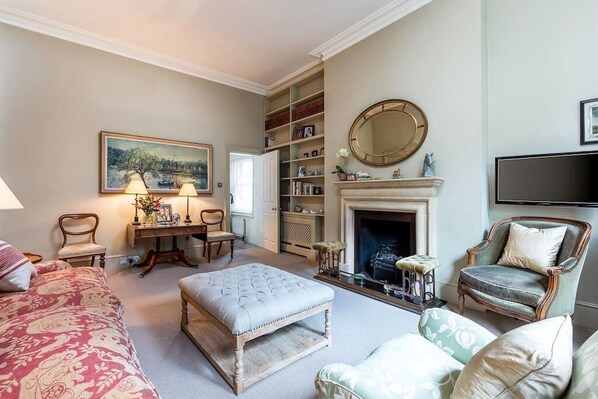 A living room with a fireplace, bookshelves, a television, and a painting on the wall.