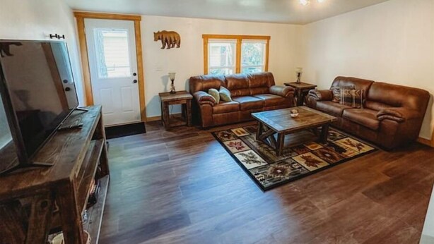 A spacious living room with a brown leather sofa set, a coffee table, and a television on a wooden stand. - Mooseyard Lodge (Shawano)