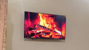 A flat-screen TV mounted on a wall displaying a fire scene.