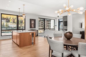 Enjoy meals in a spacious dining area with a large round table and comfortable chairs, surrounded by a stunning mountain view.