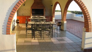 An outdoor patio with a brick fireplace, a dining table with chairs, and a tiled floor. - Edificio Asuncion (Asunción)
