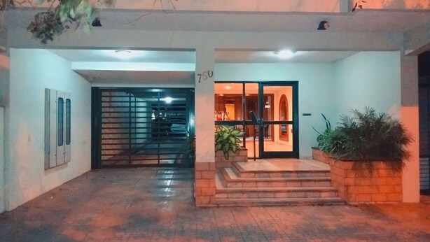 A building entrance with a glass door, a staircase, and a planter with plants. - Edificio Asuncion (Asunción)