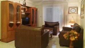 A living room with a brown sofa, a television, a cabinet, and a vase with flowers. - Edificio Asuncion (Asunción)