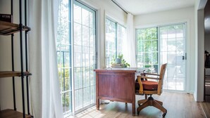 Une pièce spacieuse avec de grandes fenêtres, un bureau en bois et une chaise.