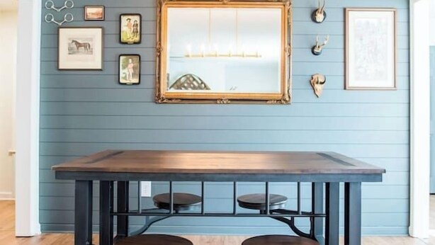 Un espace repas comprenant une table et des chaises en bois, un luminaire suspendu et des œuvres d’art accrochées au mur.