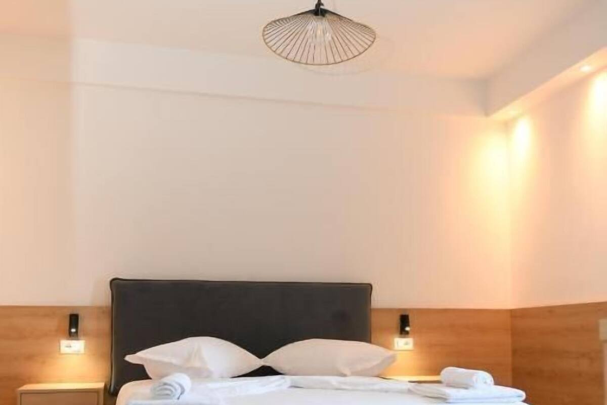 A modern bedroom with a large bed, two bedside tables, and a pendant light.