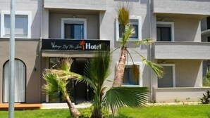 Een hotel met meerdere verdiepingen, een platte gevel, balkons en een bord met de tekst 'Villa By The Sea Hotel'.