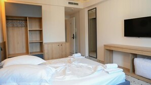 Een hotelkamer met een bed, een televisie, een kledingkast en een spiegel.