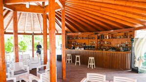 Een buitengebied met een bar, houten meubels en een bar inrichting vol flessen.