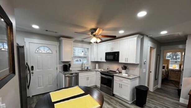 A modern kitchen with white cabinets, stainless steel appliances, and a ceiling fan. - Central Retreat C, NEW Family and Pet Friendly (Lebanon)