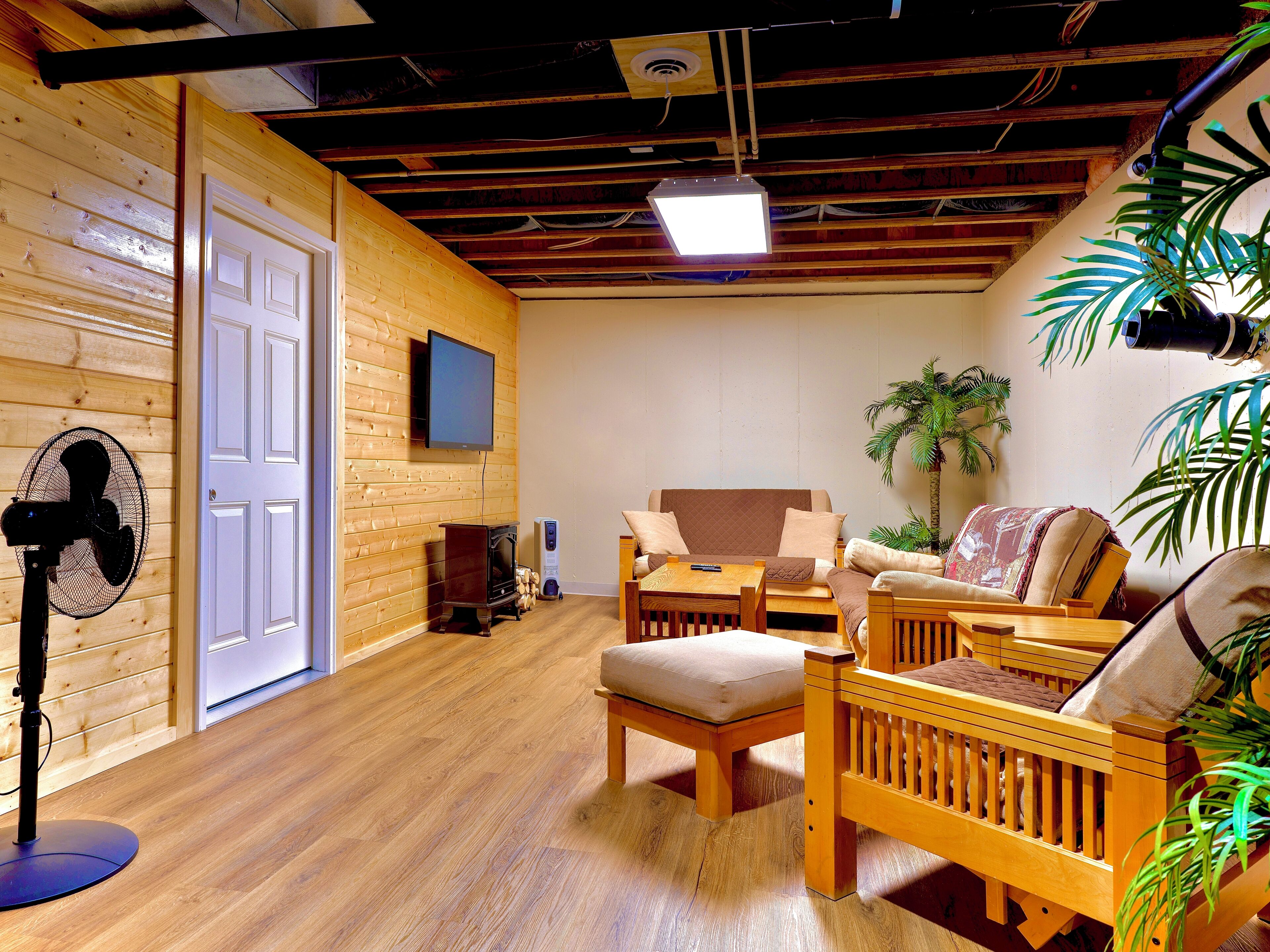 A cozy room with wooden walls, a ceiling fan, a TV, and comfortable seating.