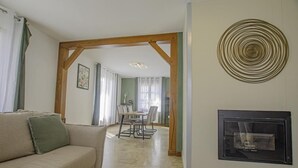 A living room with a beige sofa, a fireplace, and a dining area with a table and chairs. - Maison des 3 Lacs - CHAVANGES (CHAVANGES)