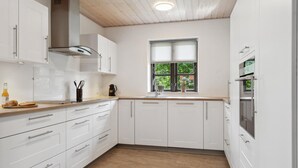 A modern kitchen with white cabinetry, a wooden countertop, a window with a view of greenery, and a built-in oven. - Awesome home in Bække with kitchen (Bække)