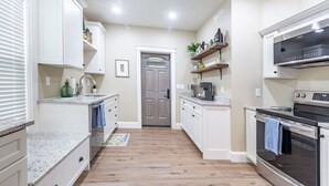 A kitchen with white cabinets, a microwave, an oven, and a coffee maker. - The Queen Place*15min to Sight&Sound*King bed*BBQ (Gordonville)