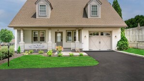 A two-story house with a front porch, a garage, and a well-maintained lawn. - The Queen Place*15min to Sight&Sound*King bed*BBQ (Gordonville)