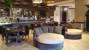 A modern lounge area with a bar, seating arrangements, and a television screen.