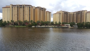 A large, multi-story hotel with a uniform architectural style, situated beside a calm body of water.