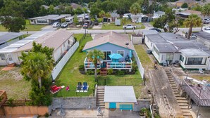 A residential area with multiple mobile homes, a central blue house with a pool, and a dock extending into a body of water.
