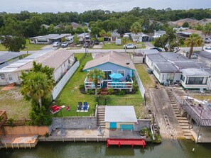 Stunning home with a balcony and pool, surrounded by a white fence and a serene water view.