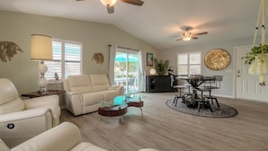 A spacious living room with a leather sofa, glass coffee table, and a dining area with a round table and chairs.