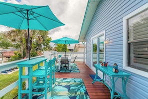 A covered patio with turquoise furniture, a table, and chairs, and a small table with decorative items. - Pelican's Canal House- Bring your Boat and Dog! (Edgewater)