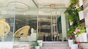 A hotel entrance with a glass door, numbered 108, and a staircase leading inside. There are potted plants on the steps and a wicker chair outside. - Hotel Jimenez Inn (Cusco)